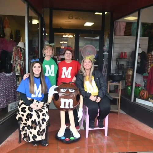 Four women in brightly colored M&M costumes, gathered on Main Street for the Boo Review event